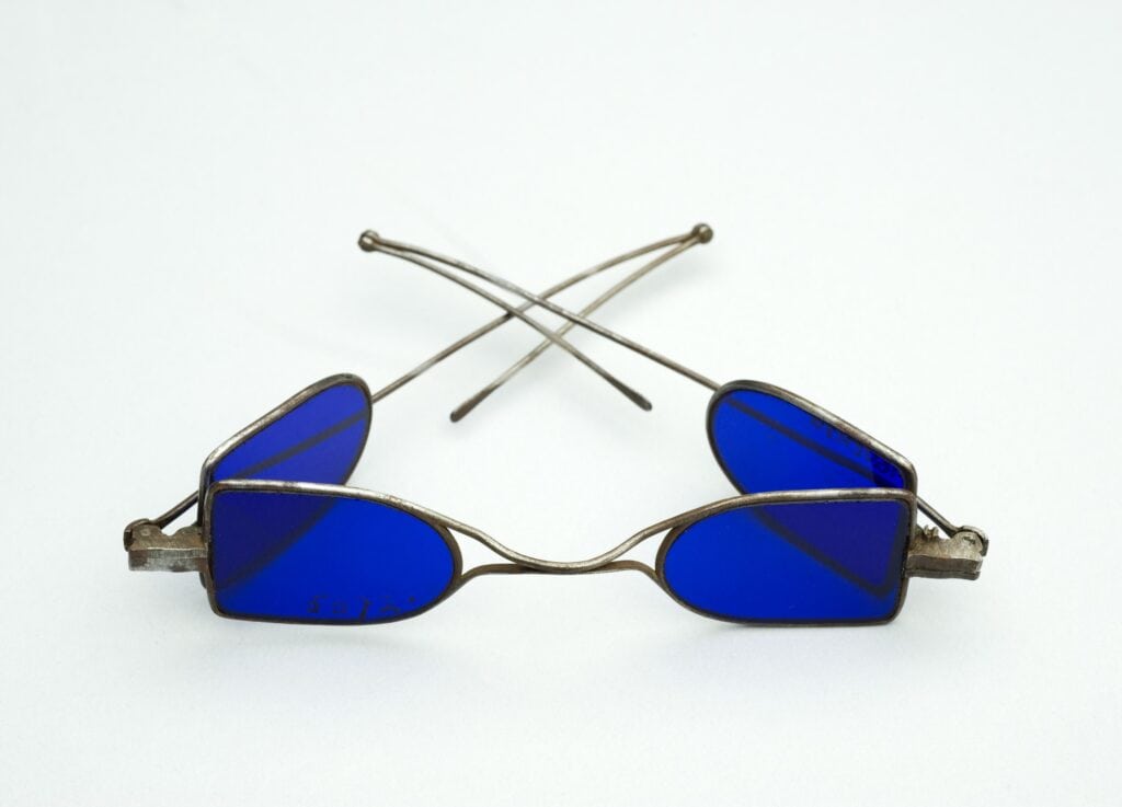 Silver framed glasses with blue lenses. The glasses have lenses on both the side and front. 